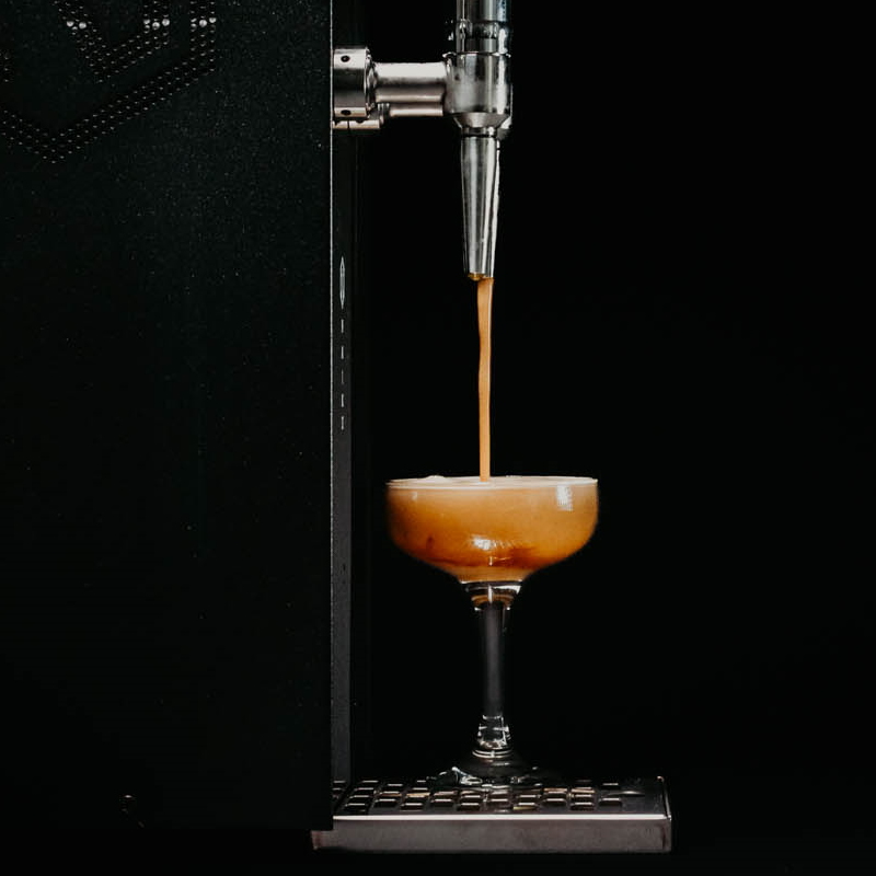 Serving Espresso Martini from a Cocktail Machine with black background and creamy velvety Espresso Martini