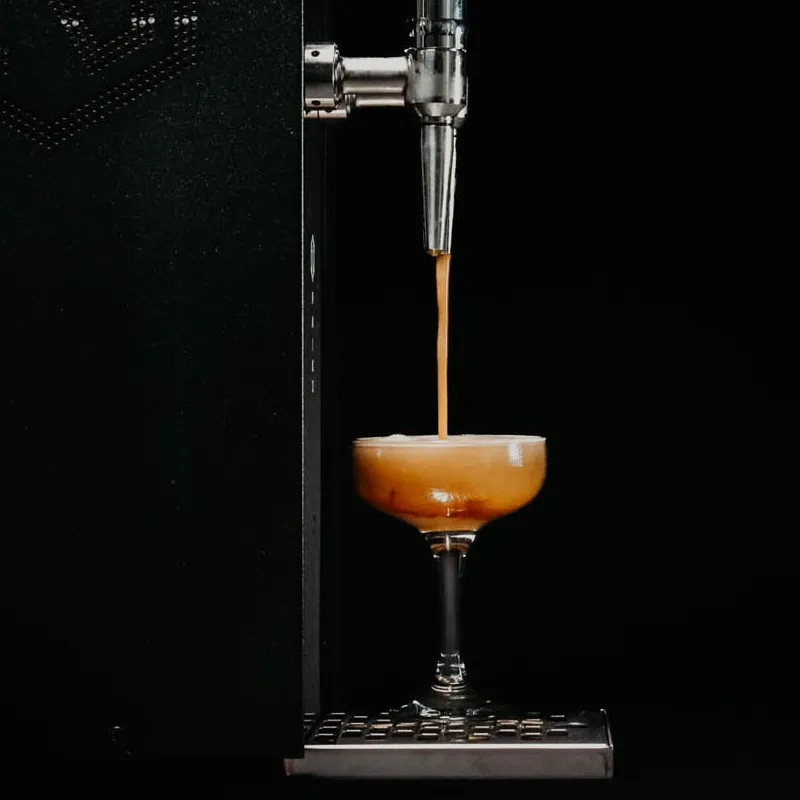 Serving Espresso Martini from a Cocktail Machine with black background and creamy velvety Espresso Martini